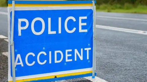 Getty Images Blue sign on road with POLICE ACCIDENT in bold white letters.
