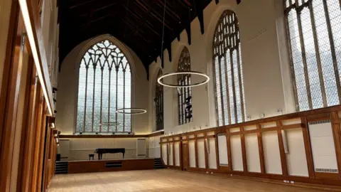 Shaun Whitmore/BBC A room inside The Halls in Norwich. There are large arched windows and circular lights suspended from the ceiling.