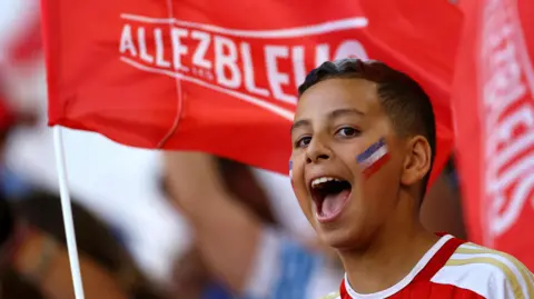 Reuters A boy with a painted face cheers while holding a flag