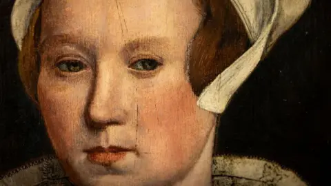 A close-up of a portrait of a Tudor woman believed to be Lady Jane Grey. She has reddish hair under a white linen cap. She is looking left.