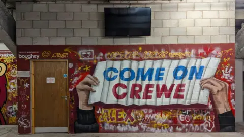 David Platt A pair of hands are pictured holding a large white banner with the words Come on Crewe in the middle.