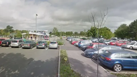 A Google Street View of the car park at the park and ride, with the central building and bus stop in the distance.