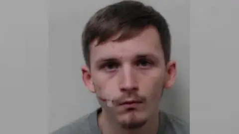 Police Scotland a police mugshot of a man whit fair hair and beard with a fresh scar across his right cheek