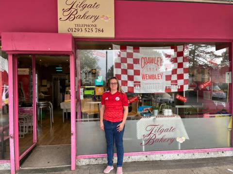 Jane Kirkham with a Crawley flag in the window of her bakery