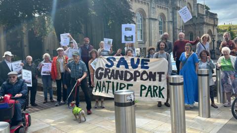 Friends of Grandpont Nature Park gathered outside County Hall with a 'Save Grandpont Nature Park' banner