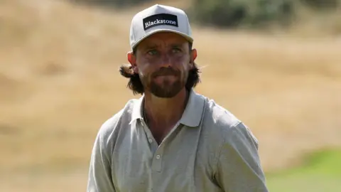 Reuters Tommy Fleetwood in a grey polo top and cap on a green.