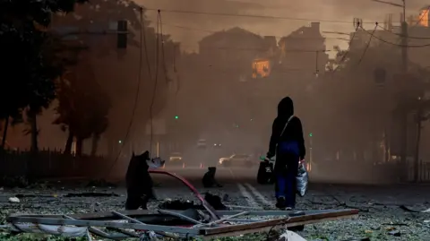 A person walks on a debris-scattered street in the aftermath of an overnight Russian missile and drone strike on Kyiv, Ukraine 24 May 2026.