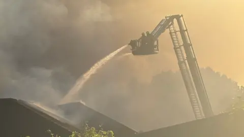 Daniel Storr Firefighters using an aerial platform to tackle the blaze with a lot of smoke obscuring the picture.