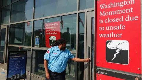 Getty Images A security guard locks the door of the Washington Monument on the National Mall after it was closed during a record-setting heat wave in the region