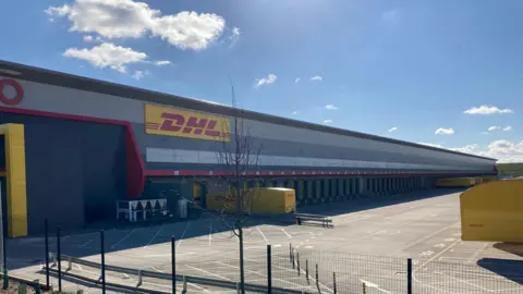 Getty Images A red "DHL" sign on the side of a yellow van. 