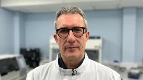 Professor Stefano Mariani, photographed in a laboratory, has says short, grey hair and wears black-framed glasses. He is wearing a white coat.