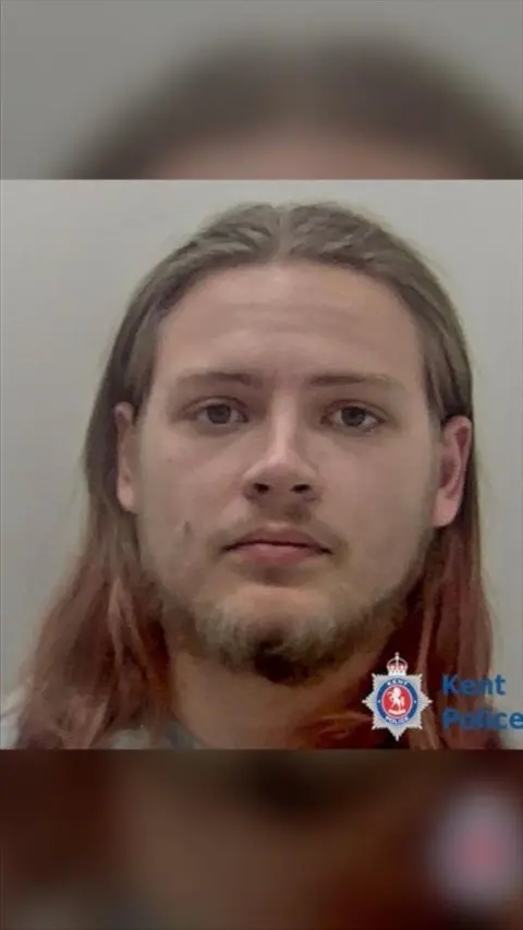 A Kent Police mug shot of a man with long, light hair and a beard.