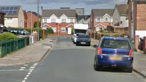 Google A street view of Kersey Road in Kirkby. There are houses lining both sides of the road and cars parked.