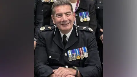 Northamptonshire Police Nick Adderley with short dark hair in a police uniform displaying five medals