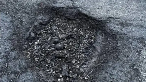 Dave Fishwick An image of a large pothole in the road surface
