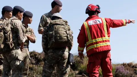 Gurkhas are seen working with firefighters