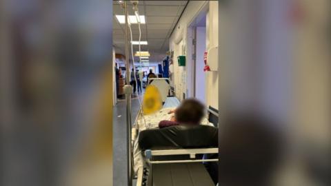 A patient on a trolley in a hospital corridor