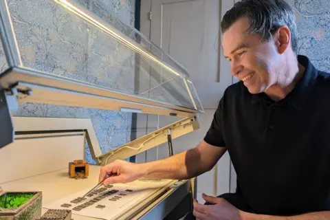 Lucinda MacPherson Jason Sandy holding a set of tweezers and moving pieces of Doves Type inside a display cabinet