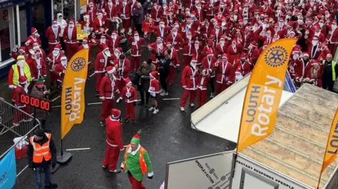 Runners taking part in the Santa run last year. They are all wearing Santa suits.