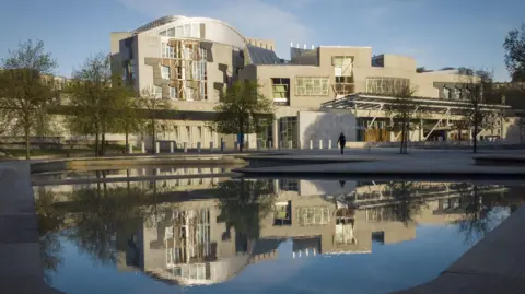 The Scottish Parliament building in Edinburgh, reflected in a pool