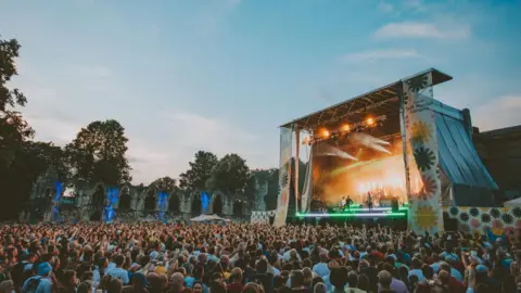A crowd of people watch a band perform in York's Museum Gardens.