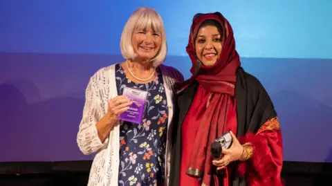 Margo Evans receiving her Great Neighbour award from Lubna Ashad 