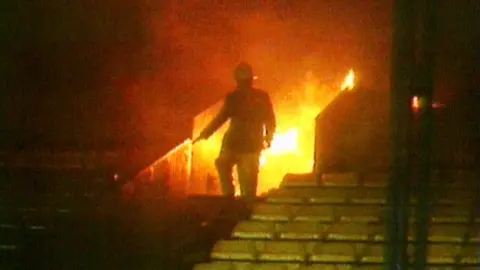 A fireman walks away from flames at a fire at Carrow Road on 25 October, 1984.