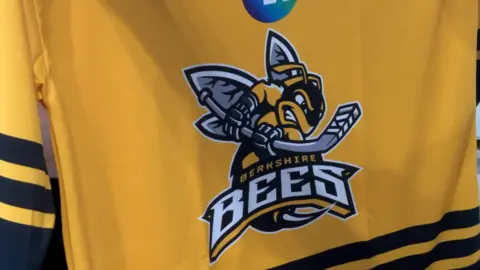 A bright yellow with black striped ice hockey shirt bears the Berkshire Bees logo in the centre