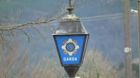 Garda sign on a black lamp post. The sign is blue background with GARDA in white writing. 