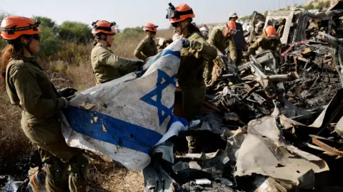 Reuters Israeli soldiers from the Home Front Command recover an Israeli flag as they search damaged cars for human remains and other evidence, following the deadly October 7 attack by Hamas gunmen from the Gaza Strip, on a field near Netivot in southern Israel.