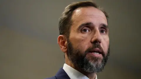 Getty Images Head shot of Jack Smith with a beard, wearing a blue suit and white shirt.