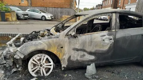 A burnt out car on a driveway