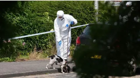 PA Media A forensic officer and sniffer dog