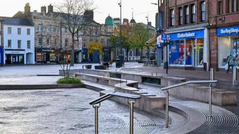 Cumberland Council Stone seating area round a newly paved walkway with shops in the background, including The Entertainer toy shop