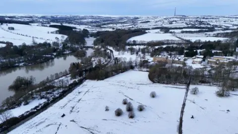 PA Media An aerial shot of snow-covered fields and country lanes, with a wide river on the left-hand side.