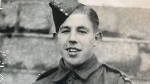 Ken Cooke A young man wearing miliary uniform is show, the picture is black and white.