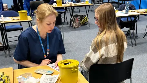 A student about to receive the Meningitis B vaccine at the University of Kent sports hall