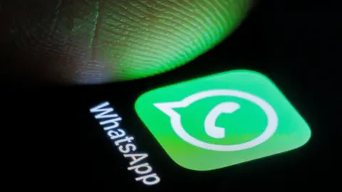 Getty Images WhatsApp logo on a phone with a thumb