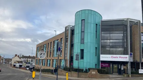 Pete Cooper/ BBC A street view of the entrance to the Hope Centre - a brick building that has a turquoise tower on the front. 