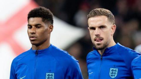 Marcus Rashford and Jordan Henderson stand for the national anthem