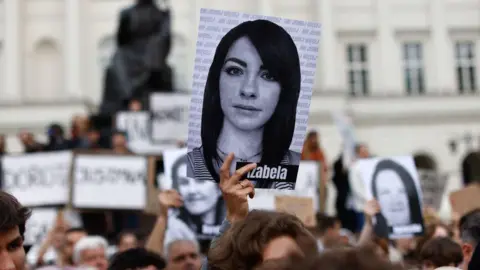 A demonstrator holds up an image showing a young woman named Izabela in downtown Warsaw on June 14, 2023, as people take to the streets to protest under the title 'Not one more' and 'Stop killing us' against the legislation on abortion