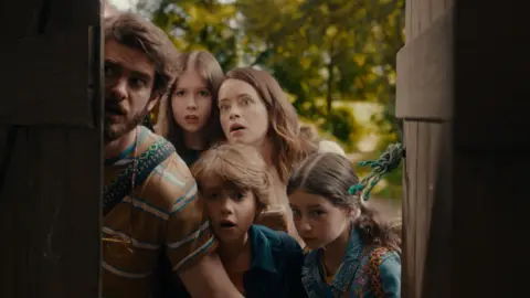 A family looks in awe through an open old door