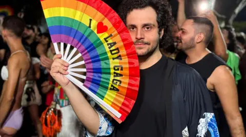 A man with a rainbow fan which says I love Lady Gaga 