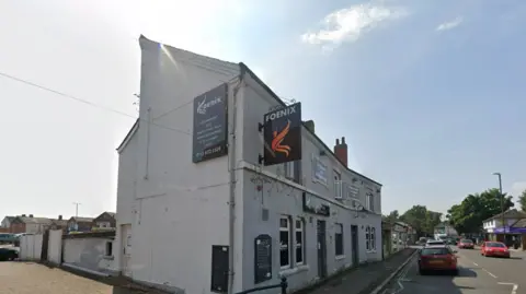 Google A sign which reads Foenix on the side of a white building with a red car to the right