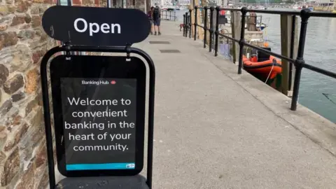 Banking hub sign on a quayside which reads 'welcome to convenient banking at the heart of your community'