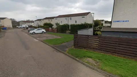 Google Maps A street view of homes in Lenzie Avenue. Several cars are parked in front of the homes. 