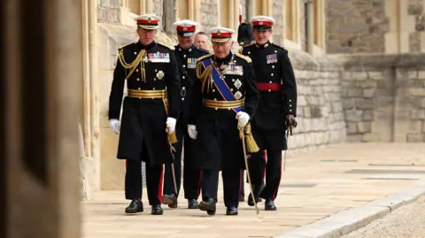 The King with the First Sea Lord and Commandant General Royal Marines, General Sir Gwyn Jenkins walking through Windsor Castle.