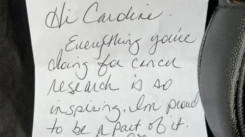 Caroline Jones A handwritten note in black pen on white paper says: "Hi Caroline, Everything you're doing for cancer research is inspiring. I'm proud to be a part of it."