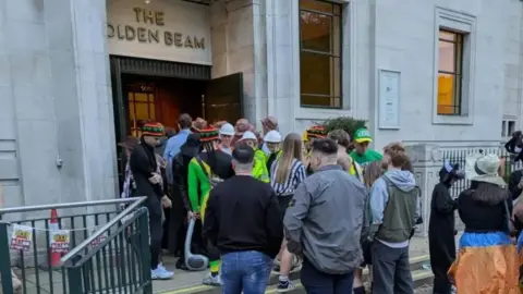 People queueing in fancy dress to enter the Golden Beam pub in Leeds