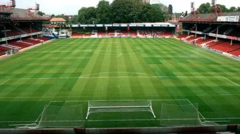 PA Media The inside of the Dell football ground in Southampton. A green pitch with red and white stands.